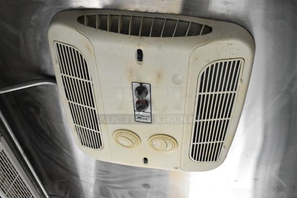 Ceiling-mounted vent in the food trailer, featuring dual vents and control knobs, moderate wear, labeled "Coleman Mach."