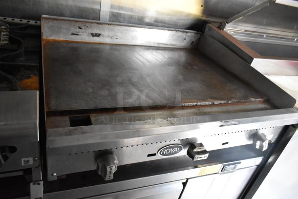 Royal flat top grill in mobile food trailer. Stainless steel, controls visible, showing signs of use. Ideal for commercial cooking.