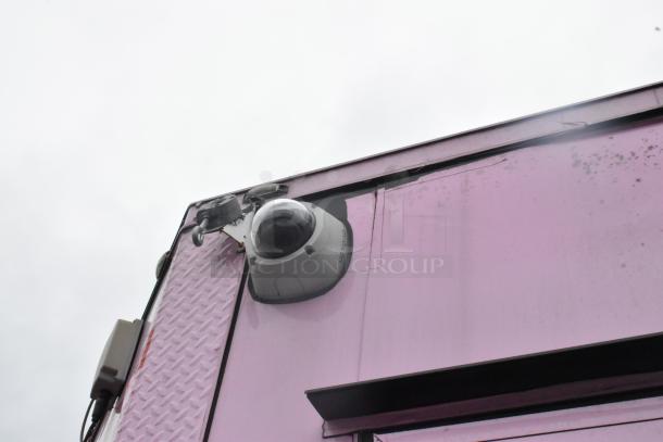 Exterior corner view of a 2020 Goodees food trailer in purple, featuring a security camera mounted on the side.