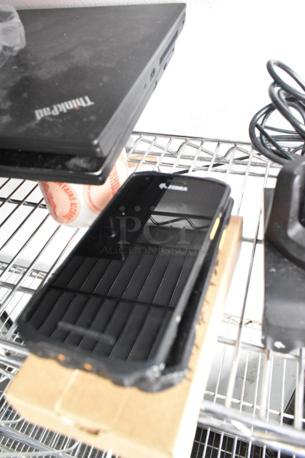 Alt text: Zebra device on a metal shelf next to a Lenovo ThinkPad laptop.