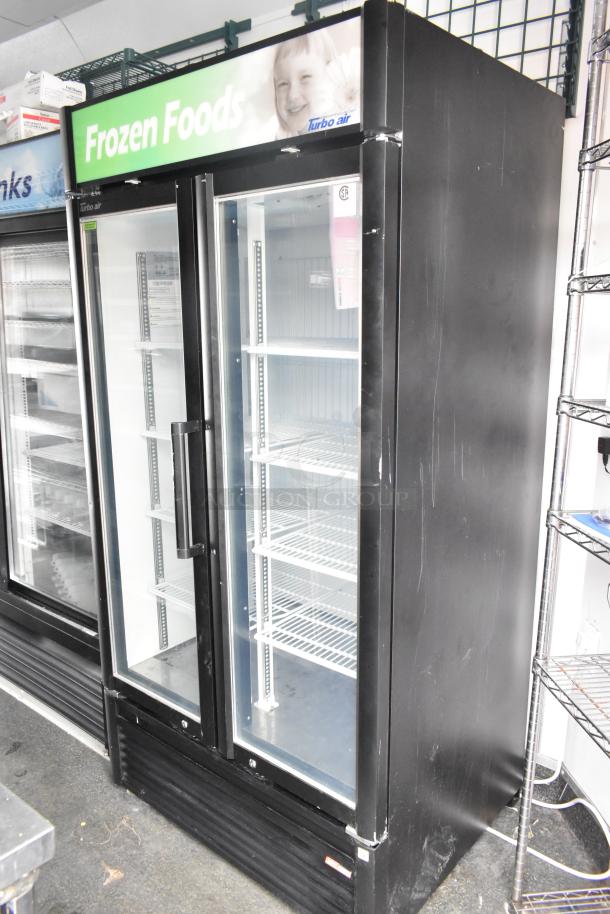 Two-door commercial freezer, labeled "Frozen Foods," Turbo Air brand, black exterior, glass doors, interior shelving.