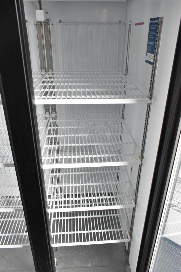 Interior view of the 2-door cooler in a 2020 Goodees food trailer, showcasing white metal shelves and a sleek black door frame.