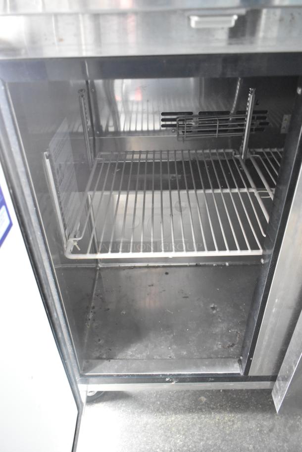 Interior view of a stainless steel cooler section in the 2020 Goodees Food Trailer, featuring wire shelving and clean surfaces.