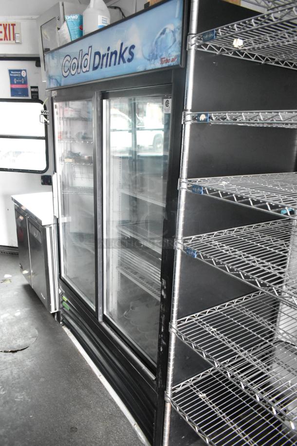 2020 Goodees food trailer interior featuring a Turbo Air two-door cooler and freezer, metal shelving, and signage.