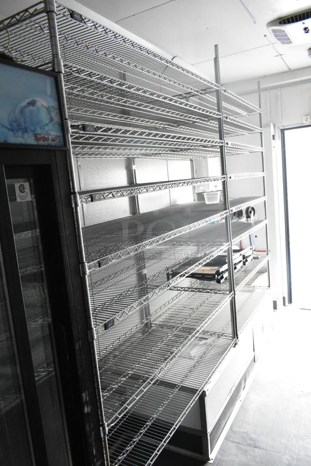 Inside view of a 2020 Goodees food trailer featuring metal shelving, a 2-door cooler, and a freezer merchandiser. Clean condition.