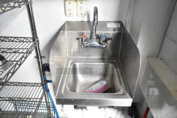 Stainless steel sink in 2020 Goodees food trailer, with soap bottle inside. Nearby metal shelving unit, switches, and plumbing visible.