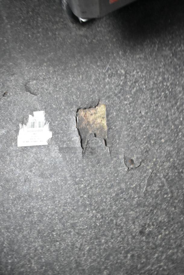 Damaged section on the surface of a Goodees food trailer floor, showing exposed underlying material.