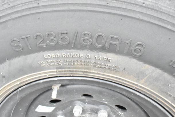 Close-up of trailer tire with markings "ST235/80R16," indicating size and "Load Range G 14 PR," indicating load capacity.