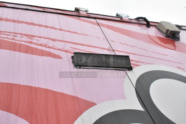Alt text: Exterior detail of a Goodees 2020 food trailer with red and pink design. Features ventilation and electrical outlets.