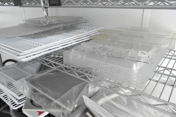 Metal shelving unit with stacked transparent and white tray covers. Labels and markings indistinct.