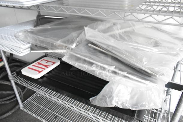 Shelves with wrapped metal items and an "EXIT" sign in a trailer interior.