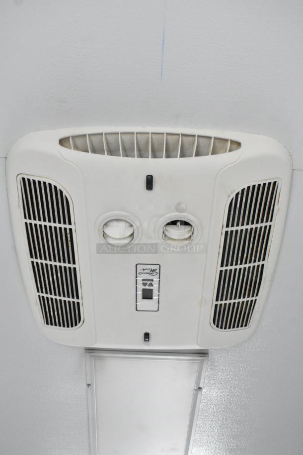 Ceiling-mounted air conditioner unit in a 2020 Southern Dimensions Group trailer. Features vents and control panel.