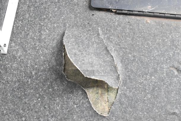 Damaged flooring of a 2020 Southern Dimensions Group Trailer. Visible surface tear reveals underlying layers.