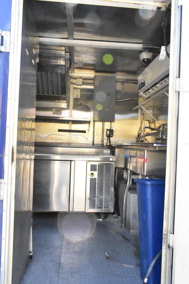 Interior view of a brand new 2019 food trailer. Features include grease hood, 2-bay fryer, coolers, and prep tables.