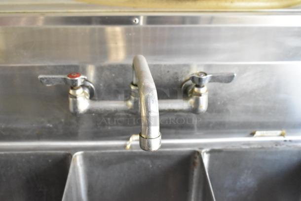 Stainless steel dual-handle faucet on commercial kitchen sink in a food trailer; well-maintained condition.