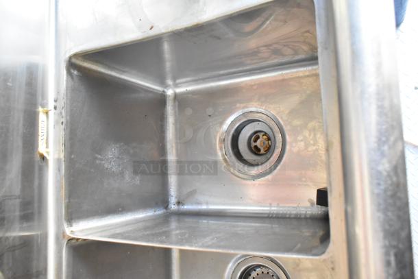 Stainless steel commercial sink with dual basins in a food trailer, marked "Sanitize" on the edge, excellent condition.