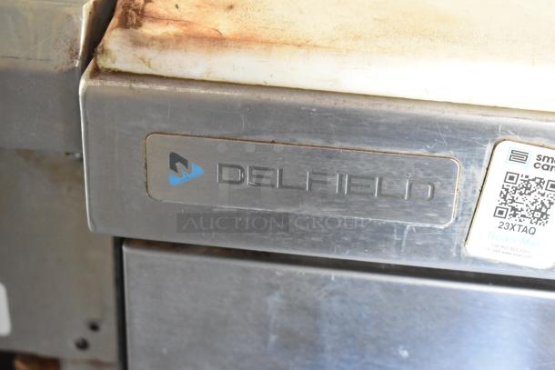 Stainless steel Delfield appliance with visible logo and QR code on an industrial food trailer.