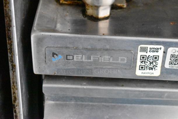 Delfield stainless steel appliance with label and QR codes, indicating brand and maintenance details.