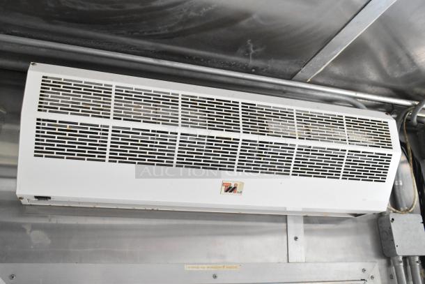 White 2019 food trailer interior with a mounted ventilation grill showing TW LLC logo. Metal piping supports the unit.