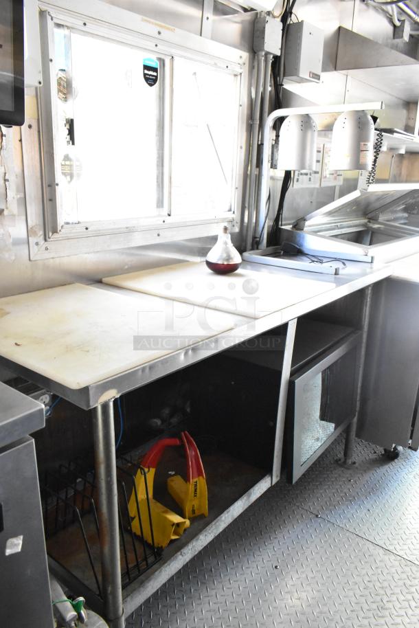 Brand new 2019 food trailer interior with prep tables, pizza prep table, mounted lamps, and storage space. Ideal for varied kitchen concepts.