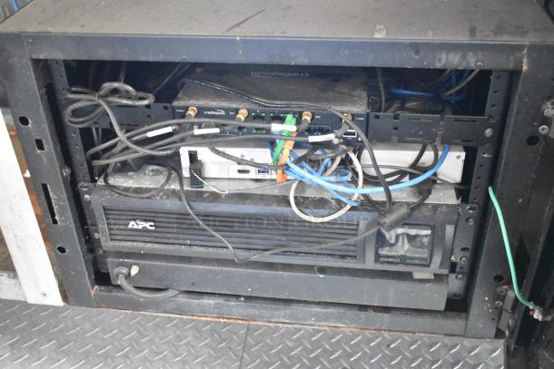 Server rack with Cradlepoint router and APC unit in a mobile kitchen trailer. Wiring visible, setup for kitchen operations.