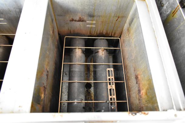 Inside view of a stainless steel fryer bay showing heating elements and grill rack, part of a fully equipped food trailer.
