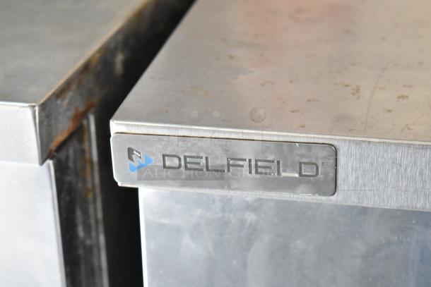 Delfield stainless steel appliance corner with visible branding, indicating quality food service equipment in a food trailer setup.