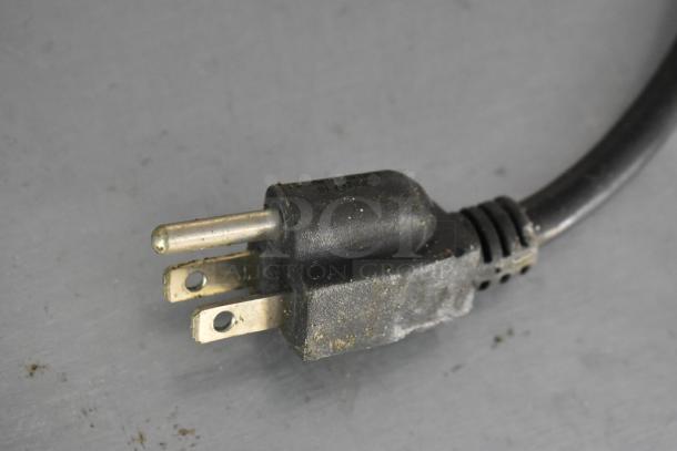 Close-up of a three-pronged electrical plug showing slight wear, on a gray surface.