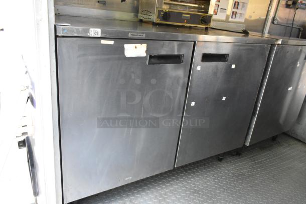 Delfield cooler in mobile kitchen trailer. Stainless steel with dual doors, ideal for food prep and storage in commercial settings.