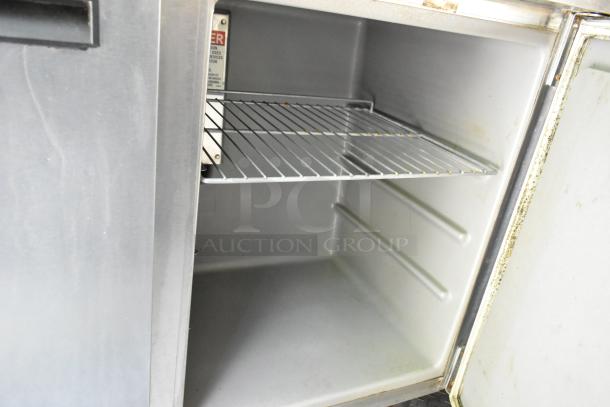 Stainless steel cooler interior with wire shelf, part of a fully outfitted 2019 mobile kitchen food trailer.
