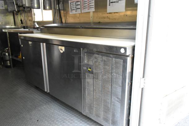 Fully outfitted 2019 food trailer interior with prep tables, storage cabinets, and cooling units; excellent condition.