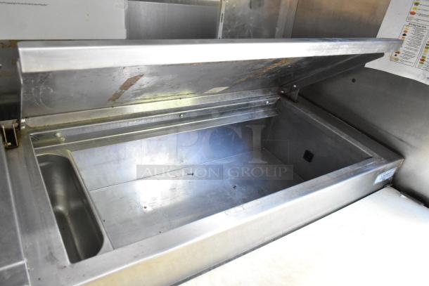 Stainless steel prep table with open lid, showing interior storage. Ideal for food trailer use. Clean and well-maintained.
