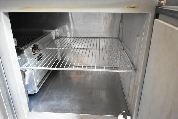 Interior view of a food trailer cooler. Features metal shelves, cooling fan, and clean stainless steel surfaces. Upper label reads "EDAMAME."