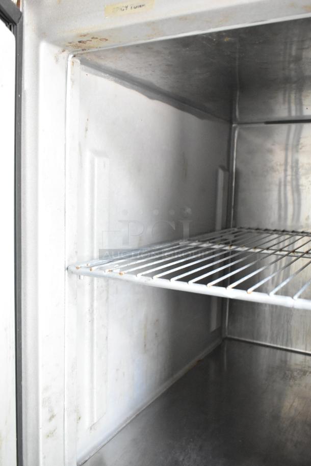 Interior of a new 2019 food trailer cooler, featuring a wire shelf. Slight discoloration on metal walls.