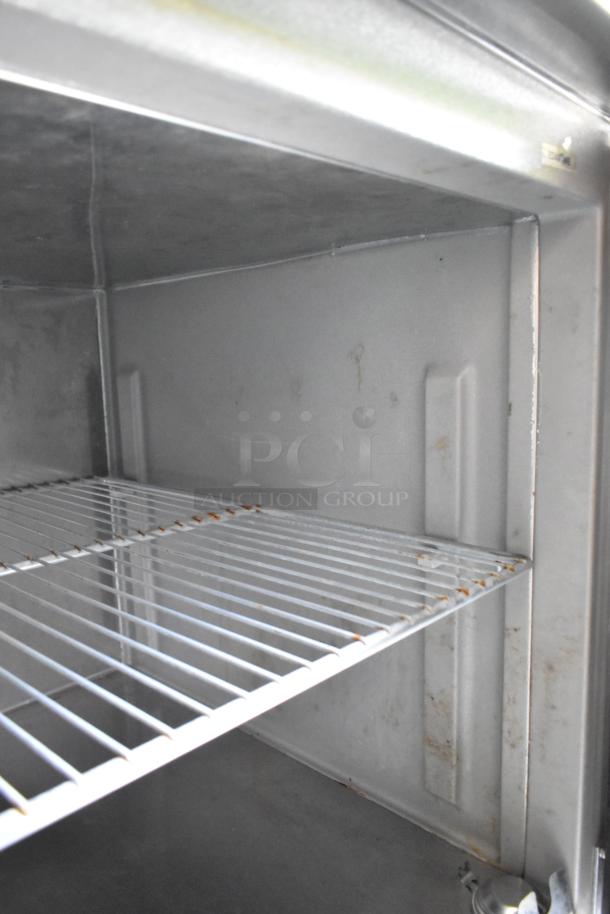 Interior view of a metal food trailer cooler with empty wire shelving. Clean and well-maintained condition.