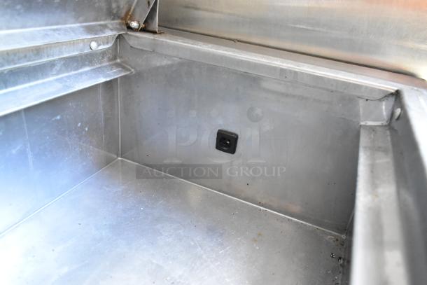 Interior view of a stainless steel food trailer's grease trap compartment, showing clean surfaces and secure fittings.