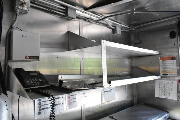 Interior view of a fully outfitted food trailer showcasing stainless steel shelves, Verizon phone, and Altronix control box.