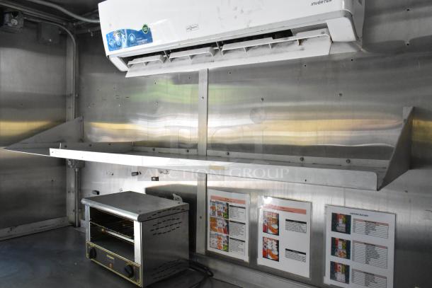 Interior of new 2019 food trailer, featuring appliances such as a stainless steel prep table and AirQuest inverter AC unit.