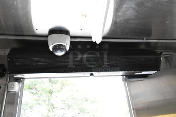 Interior of a food trailer featuring a security camera and ventilation system. Stainless steel surfaces visible.