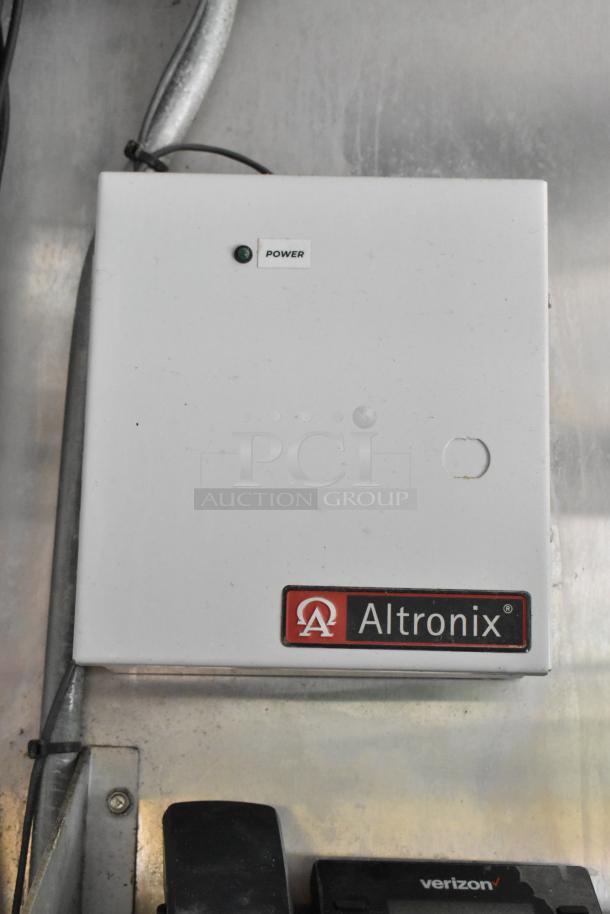 Altronix power supply box mounted on a metal wall inside a food trailer, featuring a power indicator light.
