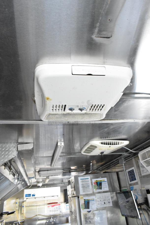 Interior view of a fully outfitted food trailer featuring appliances and fixtures, grease hood, and cooling units.