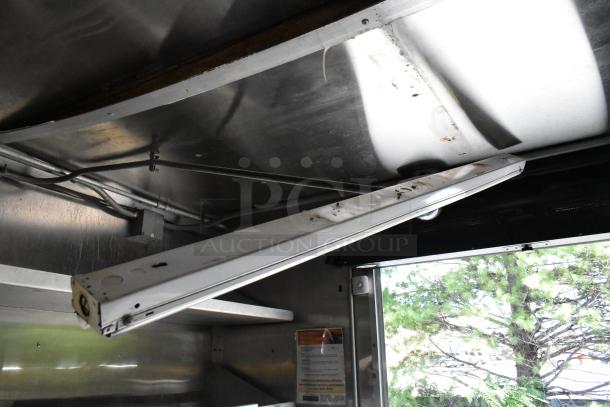 Interior of 2019 food trailer, featuring overhead grease hood and lighting fixture. Visible wiring and partial equipment view.