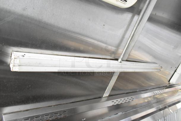 Interior of a fully outfitted food trailer from 2019, featuring a grease hood and stainless steel surfaces.