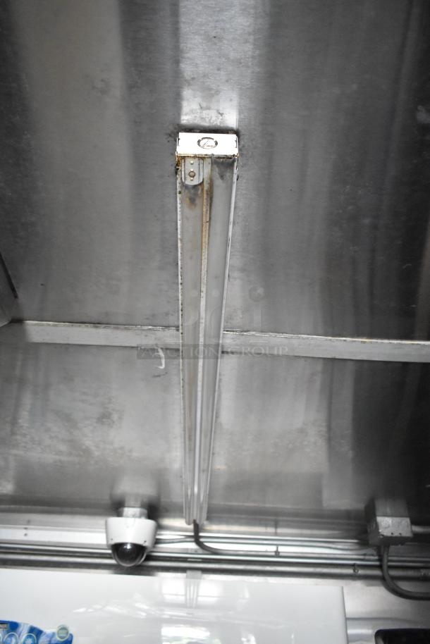 Interior view of a food trailer showing the ceiling with a mounted security camera and fluorescent lighting fixture.