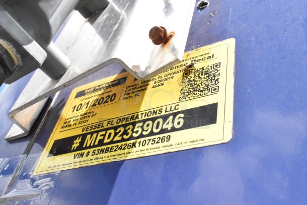 Yellow license decal on blue food trailer with registration details and QR code.