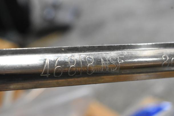 Alt text: Close-up of stainless steel utensil with "46818 NSF" marking, from a scratch and dent auction lot.