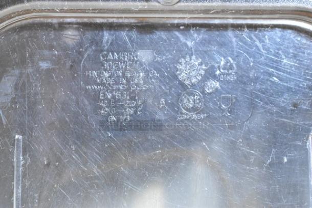 Clear bin lid with visible markings indicating the brand as Cambro, model as 30CWL, made in USA, NSF certified. Scratched surface.