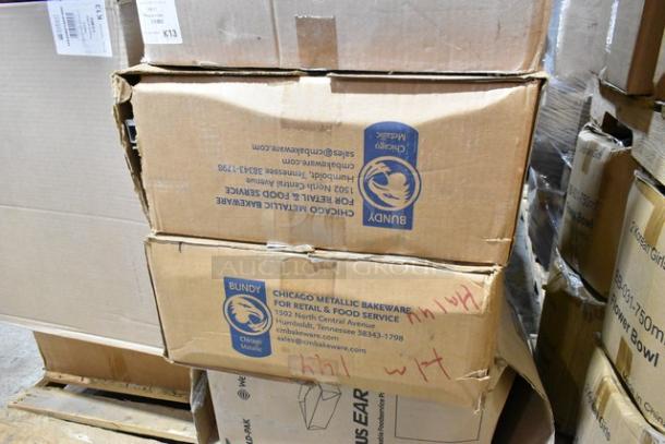Stacked boxes labeled "Chicago Metallic Bakeware" and "Bundy" with scratch and dent markings, containing food pan lids and to-go containers.