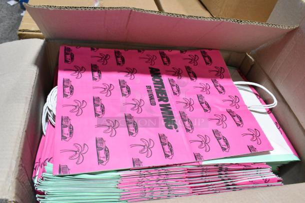 Box containing new "Another Wing by DJ Khaled" pink paper handle bags with car and palm tree design.