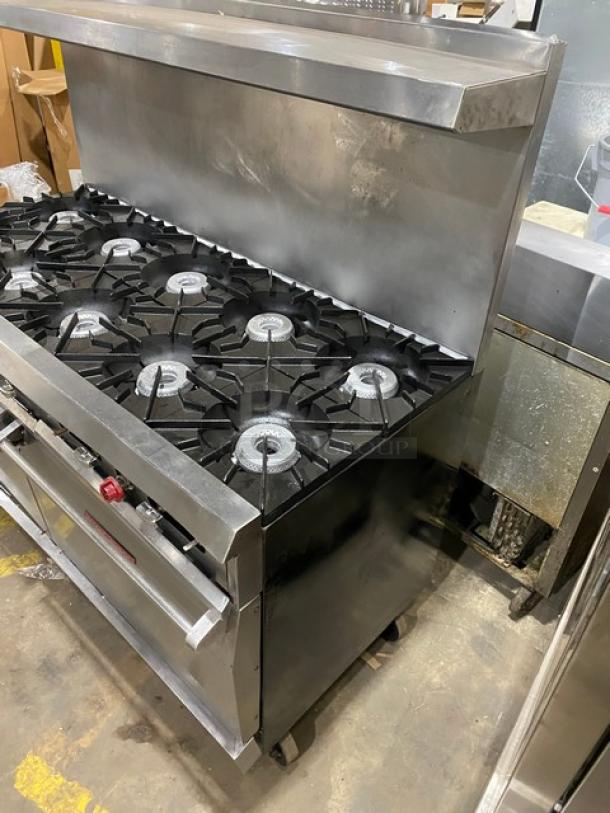 Vulcan 10-burner stainless steel range with double oven, backsplash, overhead salamander shelf, and wired oven rack on casters.